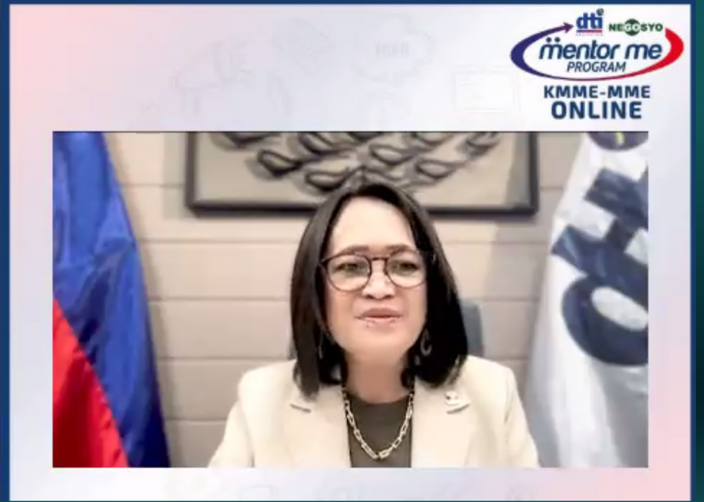 A screenshot of a DTI official speaking during the 2025 KMME-MME Online Program, with the DTI Mentor ME Program banner in the background.