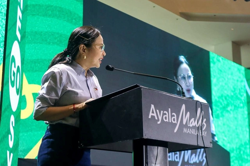 DTI Secretary Cristina A. Roque delivers a speech at the Creative Entrepreneurship Summit 2025 held at Ayala Malls Manila Bay, with a backdrop displaying the Go Negosyo branding.
