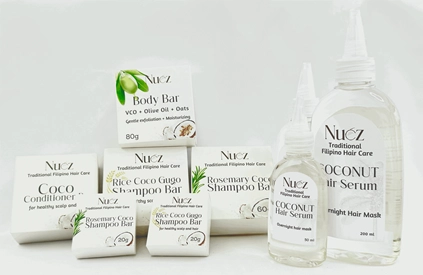 A collection of "Nuez" brand Traditional Filipino Hair Care and skin care products, including various shampoo bars, a conditioner bar, a body bar, and bottles of coconut hair serum, arranged neatly against a plain white background.