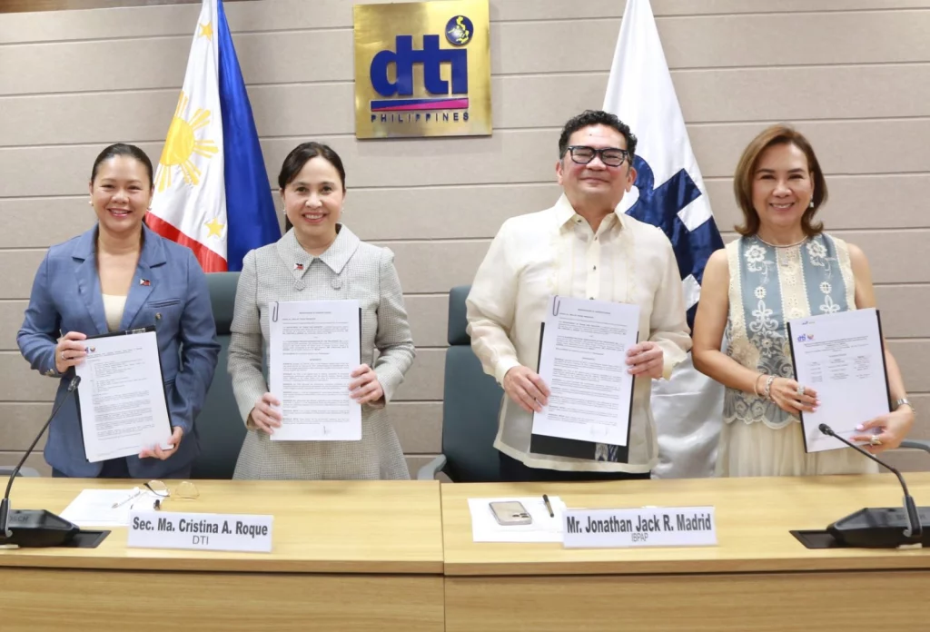 From left to right: DTI-CIG Supervising Head, Assistant Secretary Nylah Rizza D. Bautista, DTI Secretary Ma. Cristina A. Roque, IBPAP President and CEO, Mr. Jonathan Jack R. Madrid, and IBPAP COO, Ms. Celeste B. Ilagan, are seated at a table, holding signed documents.