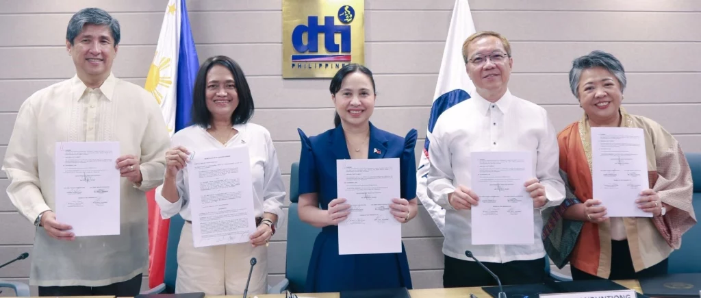 In photo: From L to R: JFC Vice President and Head of Public Affairs Atty. Raul Academia, DTI-ROG Undersecretary Blesila A. Lantayona, DTI Secretary Cristina A. Roque, JFC Philippines Chief Executive Officer and Head for Jollibee Global Joseph Tanbuntiong, JGF President Ma. Gisela Tiongson. Standing in front of a backdrop with the DTI Philippines logo, indicating the formal signing of a memorandum of understanding (MOU) between the Department of Trade and Industry (DTI), Jollibee Foods Corporation (JFC), and the Jollibee Group Foundation (JGF). This MOU aims to support and enhance the capabilities of micro, small, and medium enterprises (MSMEs) in the Philippines.