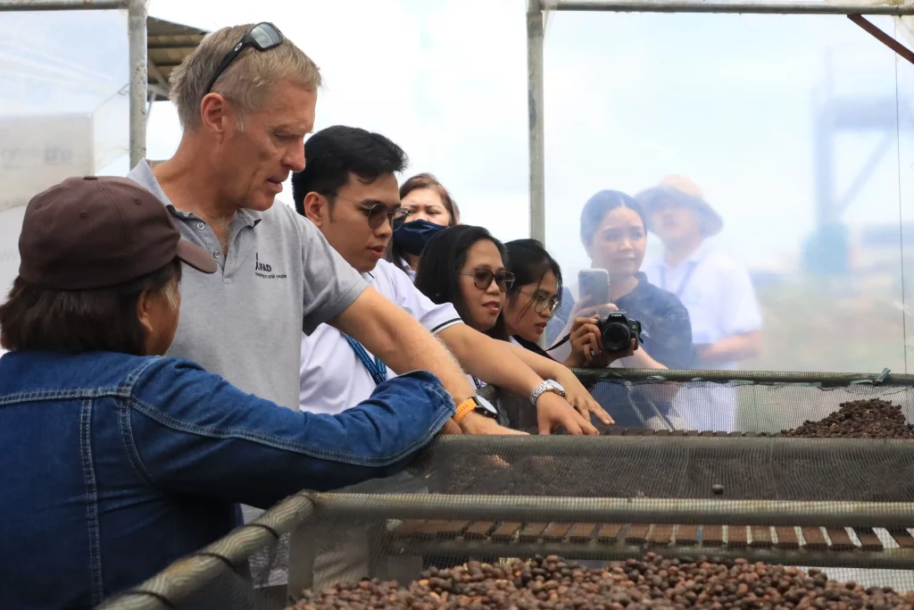 DTI and IFAD officials observe coffee beans being dried at a project-supported facility in Bukidnon, showcasing the RAPID Growth Project’s support for post-harvest processing and agro-enterprise development in rural communities.