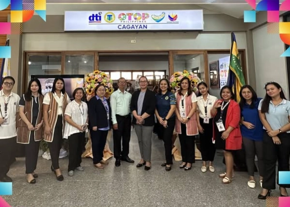 DTI and provincial officials standing in front of the newly inaugurated OTOP Philippines Hub Cagayan at Gasat Hall, marking the official launch with floral arrangements and signage highlighting support for local MSMEs.