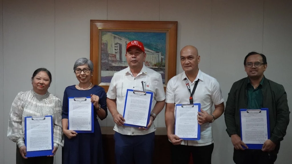 From left to right: PDCB Division Chief Engr. Jocelyn C. Carrasco, PODCB Executive Director Doris U. Gacho, UE President Dr. Zosimo M. Battad, UE - Manila College of Engineering Dean Rogelio B. Aniez, Jr., and Department Chairperson Mark Anthony L. Escober are posing for a photo, likely at the MOU signing ceremony. They are holding documents, possibly the signed agreement.