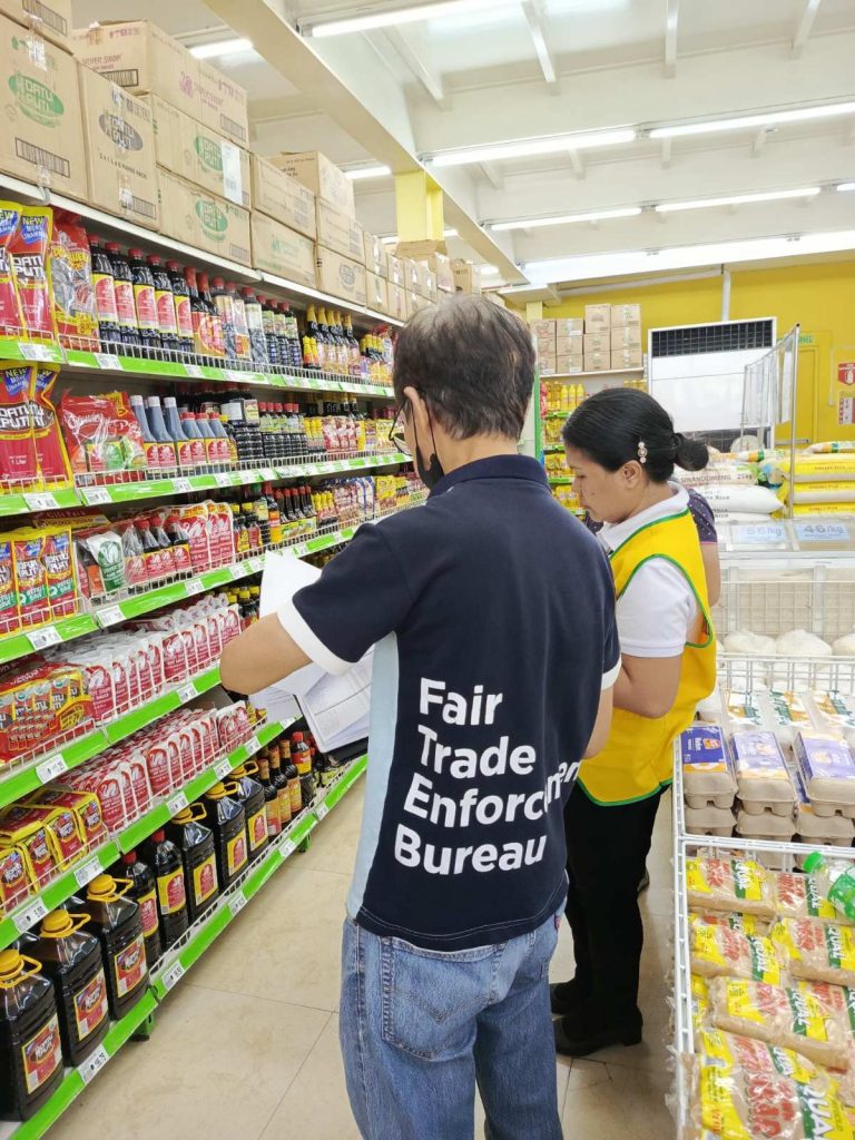 DTI Fair Trade Enforcement Bureau personnel inspect grocery store shelves stocked with bottled goods to ensure price stability and compliance with the Price Act in storm-affected areas.