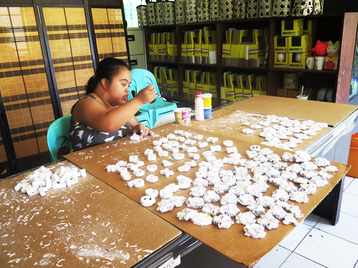 A person with disability painstakingly works on the recycled materials for 4K's handicrafts