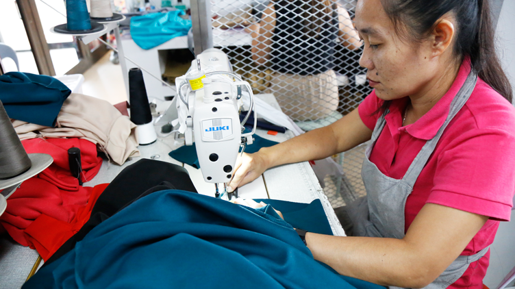 An employee of ATE working on a dress on a sewing kit