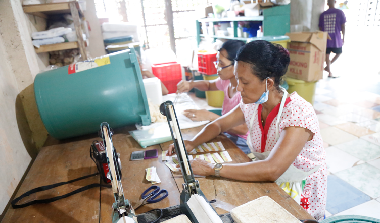An employee of Nat’s Delicacies and Bakery Products printing and cutting out labels for their products