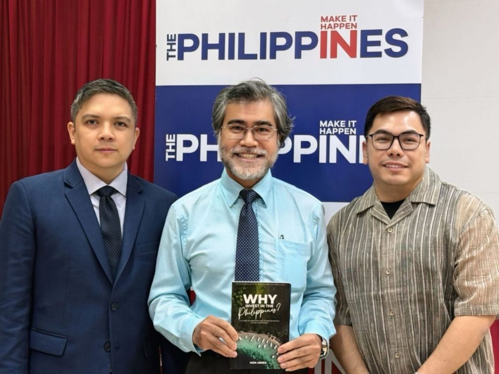 From left to right: Commercial Attaché Enrico Mariano (PTIC Ho Chi Minh City), Mr. Le Tuan Khanh (Vice President, Vietnam-ASEAN Friendship Association), and Mr. Mon Abrea (CEO, Asian Consulting Group) standing in front of a 'The Philippines Make It Happen' backdrop, with Mr. Abrea holding a book titled 'WHY Philippines?'