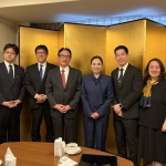 A group photo shows Department of Trade and Industry (DTI) Secretary Cristina A. Roque and several staff members, including DTI Assistant Secretaries Chua and Layug, and DTI-PTIC Tokyo STR Dita Angara-Mathay, posed with Japanese business representatives including Mr. Shinji Fukami, Senior General Manager of International Business Division, Mr. Masao Osumi, General Manager, and Ms. Narumi Saito & Mr. Hidetaka Yamanokuchi from the International Business Division. They stand in a room with a gold folding screen backdrop. In front of them on the table are cups of coffee and refreshments.