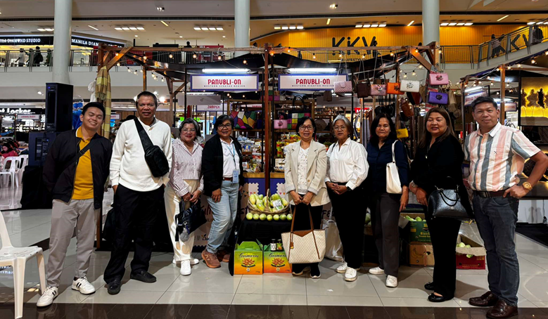 At KULTURA Fest 2025, DTI Region 6 Regional Director Rachel Nufable, wearing a brown blazer, and DTI staff visit the Panublion Western Visayas booth. The booth displays local products. The DTI staff poses in front of it. The booth is in a mall.