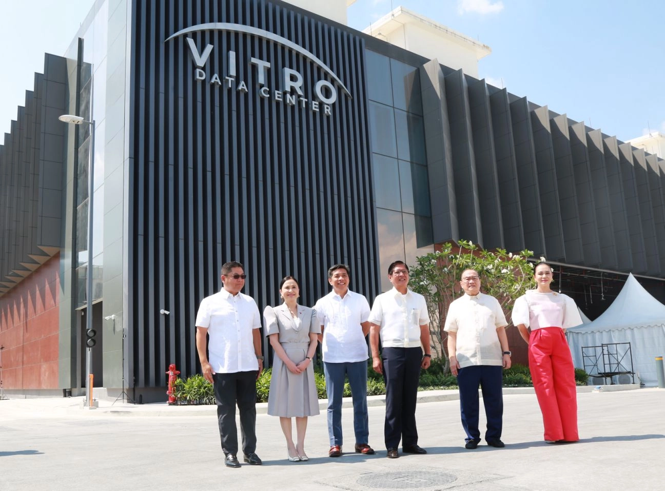 Six individuals stand in front of the VITRO Sta. Rosa Data Center building in the Philippines, celebrating its inauguration attended by DTI Secretary Cristina A. Roque and President Ferdinand R. Marcos Jr.