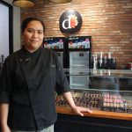 Ms. Aquino of Dahlia, a Filipina chocolatier, stands proudly in her Cebu shop, showcasing chocolate creations and pastries.